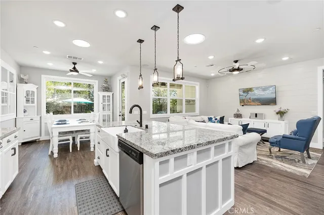 a large white kitchen with stainless steel appliances kitchen island granite countertop a sink and cabinets