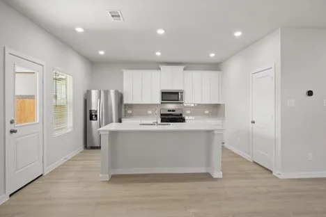 a kitchen with stainless steel appliances granite countertop a refrigerator sink and white cabinets