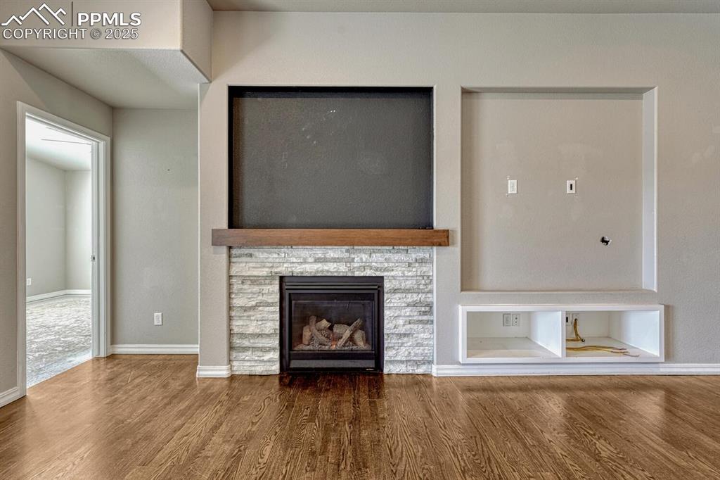 8437 Salt Brush Road Colorado Springs, CO 80908 - Photo 11 of 45 Step into the family room, where a ceiling fan, stone fireplace, and stunning wood floors converge to create a warm and inviting atmosphere, complete with a textured ceiling, walkout to the covered patio, and recessed lighting.