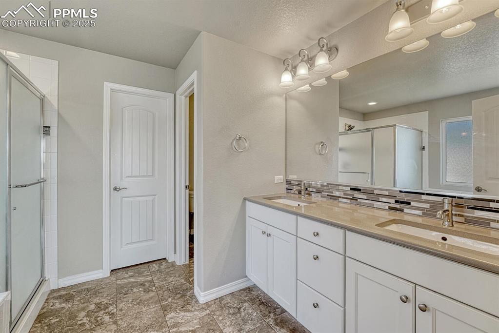 8437 Salt Brush Road Colorado Springs, CO 80908 - Photo 13 of 45 Unwind in style in the primary bathroom, featuring a spa-inspired shower stall, a tranquil garden tub, double vanity, and elegant decorative backsplash.