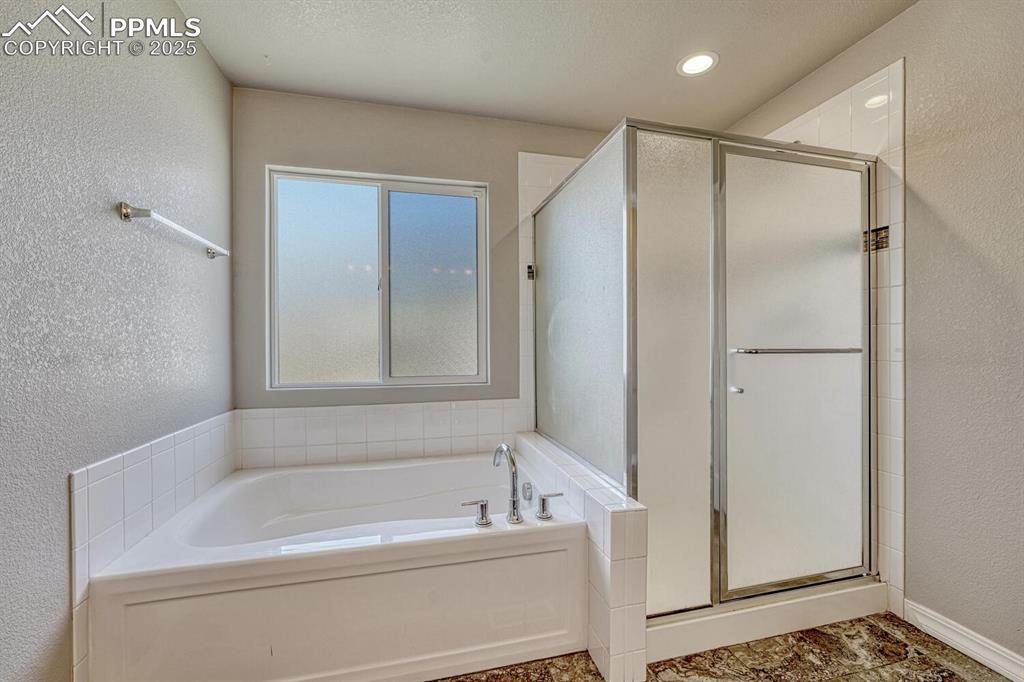 8437 Salt Brush Road Colorado Springs, CO 80908 - Photo 14 of 45 Unwind in style in the primary bathroom, featuring a spa-inspired shower stall, a tranquil garden tub, double vanity, and elegant decorative backsplash.