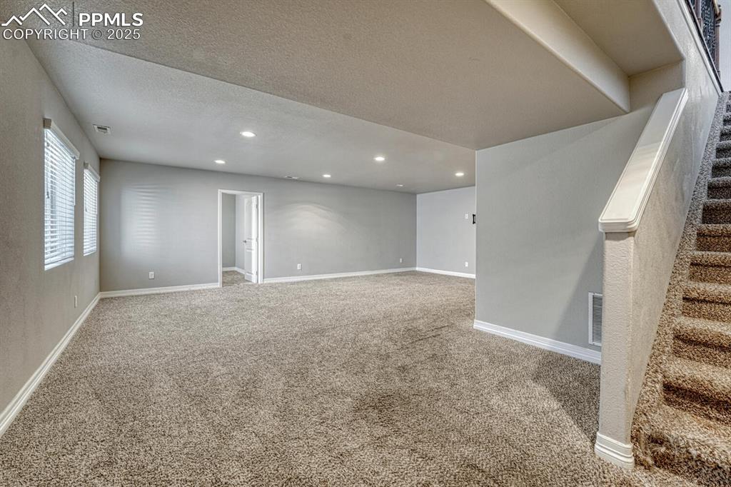 8437 Salt Brush Road Colorado Springs, CO 80908 - Photo 19 of 45 Step into our inviting living room, featuring soft carpet floors, a textured ceiling, and recessed lighting that sets the tone for a cozy retreat.
