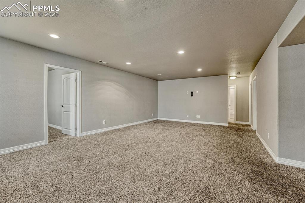 8437 Salt Brush Road Colorado Springs, CO 80908 - Photo 20 of 45 Step into our inviting living room, featuring soft carpet floors, a textured ceiling, and recessed lighting that sets the tone for a cozy retreat.