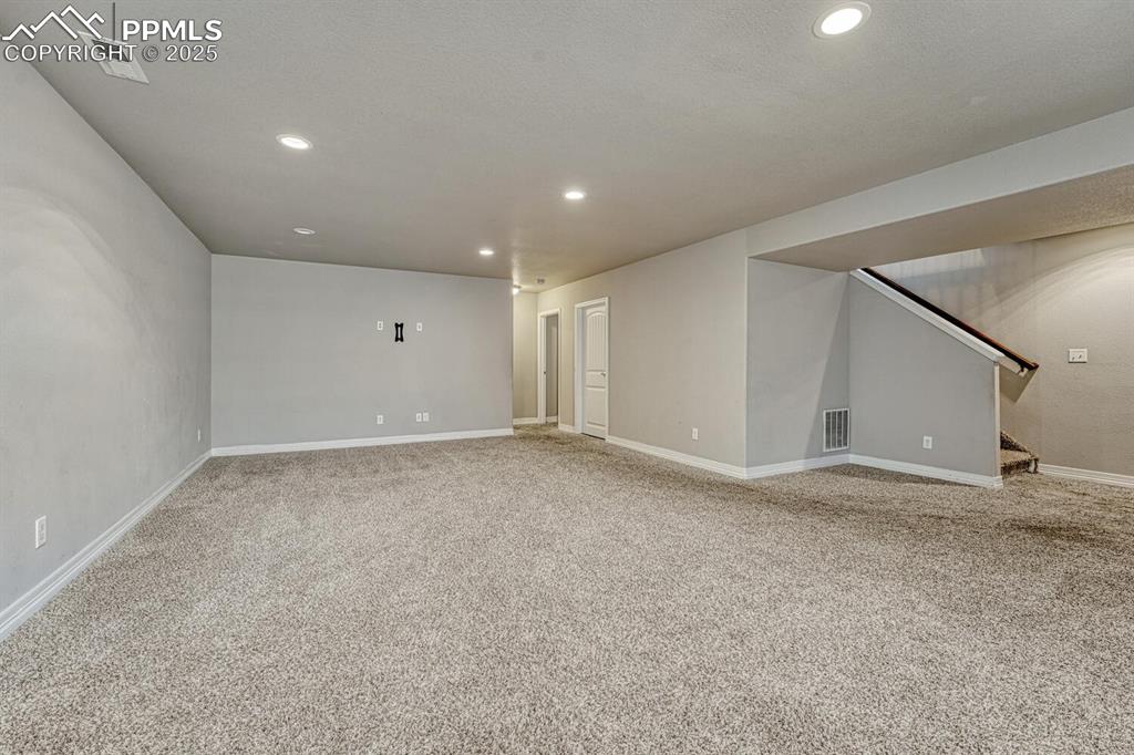 8437 Salt Brush Road Colorado Springs, CO 80908 - Photo 21 of 45 Step into our inviting living room, featuring soft carpet floors, a textured ceiling, and recessed lighting that sets the tone for a cozy retreat.