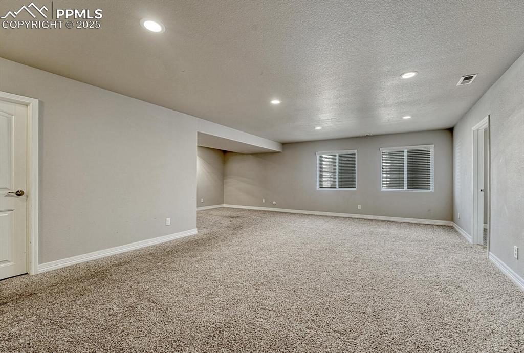 8437 Salt Brush Road Colorado Springs, CO 80908 - Photo 22 of 45 Step into our inviting living room, featuring soft carpet floors, a textured ceiling, and recessed lighting that sets the tone for a cozy retreat.