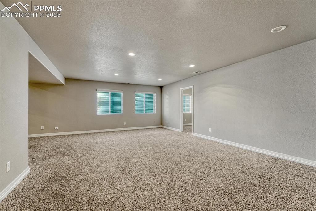 8437 Salt Brush Road Colorado Springs, CO 80908 - Photo 23 of 45 Step into our inviting living room, featuring soft carpet floors, a textured ceiling, and recessed lighting that sets the tone for a cozy retreat.