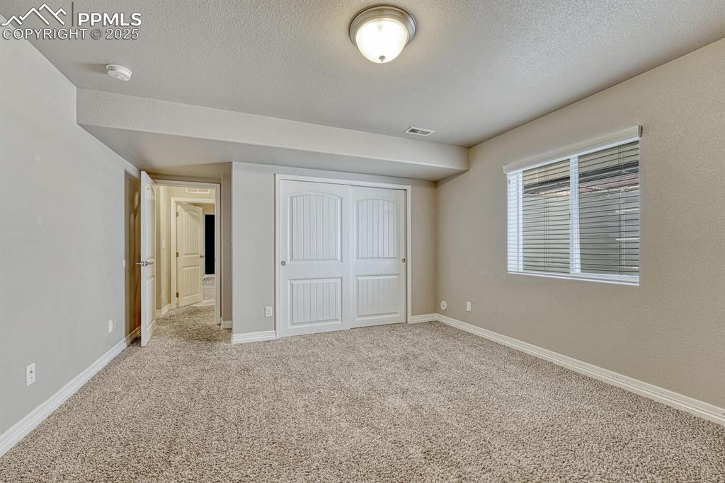 8437 Salt Brush Road Colorado Springs, CO 80908 - Photo 26 of 45 Discover the possibilities in this spare bedroom, complete with a closet, soft carpet, and a ceiling with a touch of texture.