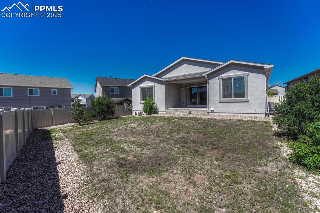 8437 Salt Brush Road Colorado Springs, CO 80908 - Photo 35 of 45 The back of the property showcases charming stucco siding and a safely enclosed backyard, ready for your personal touch.