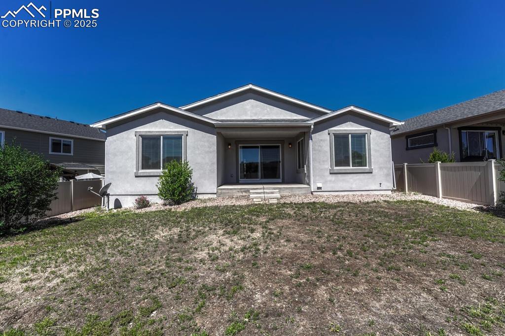 8437 Salt Brush Road Colorado Springs, CO 80908 - Photo 36 of 45 The back of the property showcases charming stucco siding and a safely enclosed backyard, ready for your personal touch.