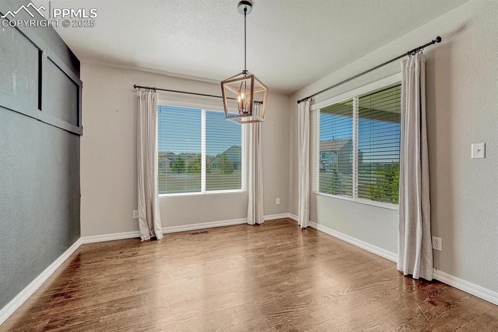 8437 Salt Brush Road Colorado Springs, CO 80908 - Photo 45 of 45 Experience a dining space that beautifully blends warmth and sophistication, showcasing rich wood floors, a magnificent chandelier, and intriguing textured details on walls and ceiling.
