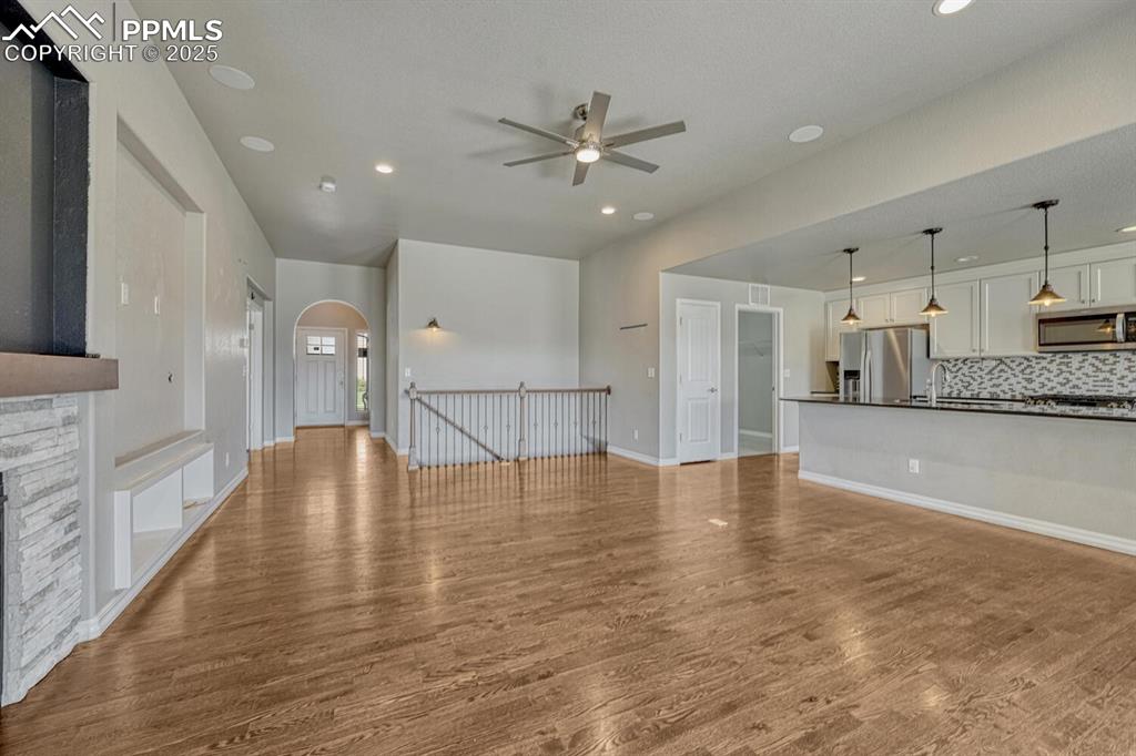 8437 Salt Brush Road Colorado Springs, CO 80908 - Photo 7 of 45 Step into the family room, where a ceiling fan, stone fireplace, and stunning wood floors converge to create a warm and inviting atmosphere, complete with a textured ceiling, walkout to the covered patio, and recessed lighting.
