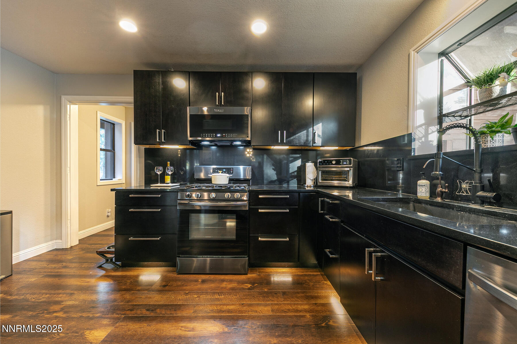25 Winterberry Court Reno, NV 89511 - Photo 11 of 31 a kitchen with stainless steel appliances kitchen island granite countertop a stove a sink and a microwave