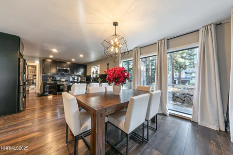 a dining room with wooden floor a chandelier a wooden table and chairs