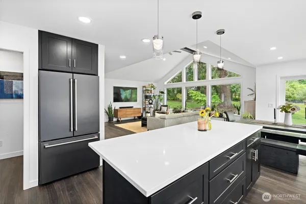 a view of a kitchen with kitchen island a large counter top space stainless steel appliances and a large window