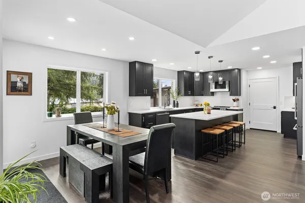 a room with stainless steel appliances kitchen island granite countertop a dining table chairs and view living room