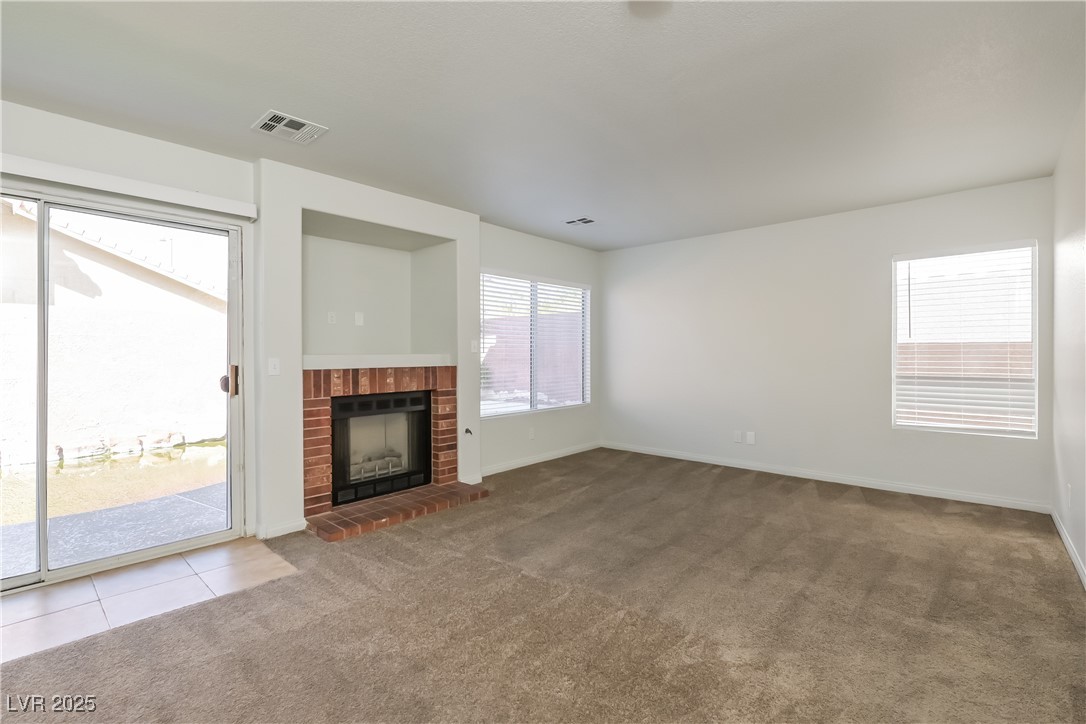 8906 Chapman Point Las Vegas, NV 89129 - Photo 2 of 13 Unfurnished living room featuring light carpet and a brick fireplace