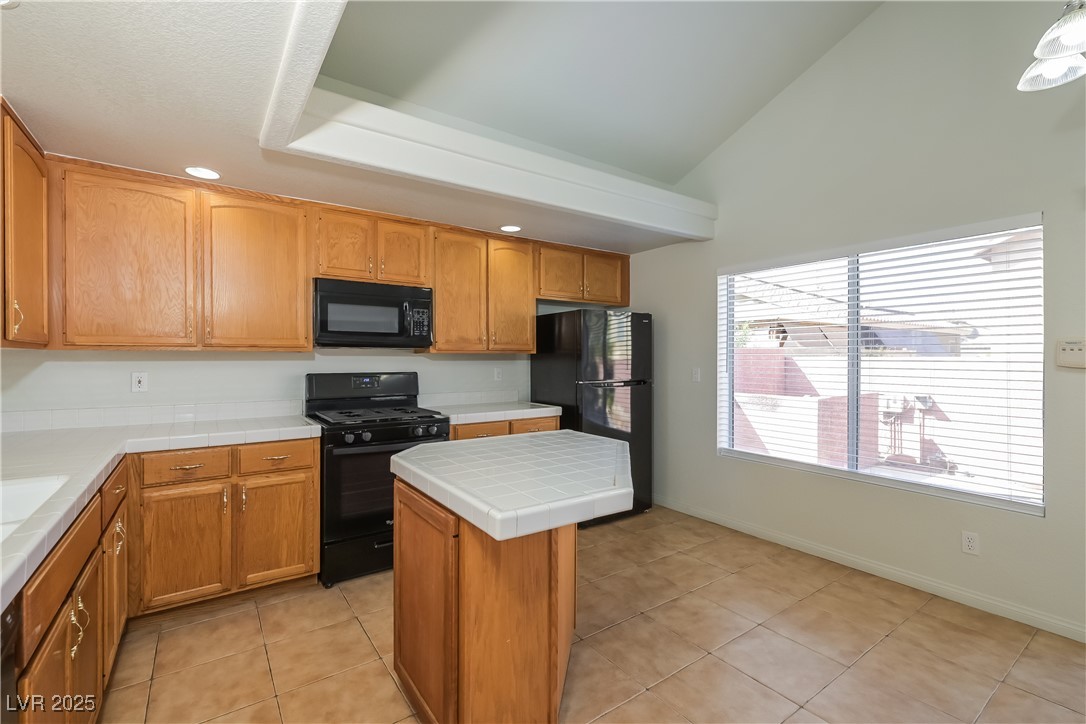8906 Chapman Point Las Vegas, NV 89129 - Photo 6 of 13 Kitchen featuring light tile patterned floors, black appliances, brown cabinetry, recessed lighting, and a kitchen island