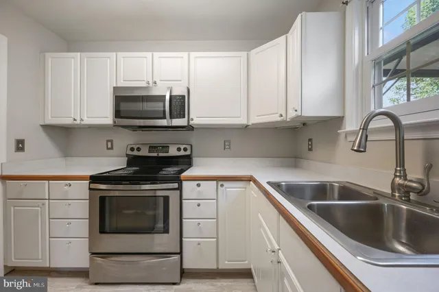 a kitchen with white cabinets appliances and a sink
