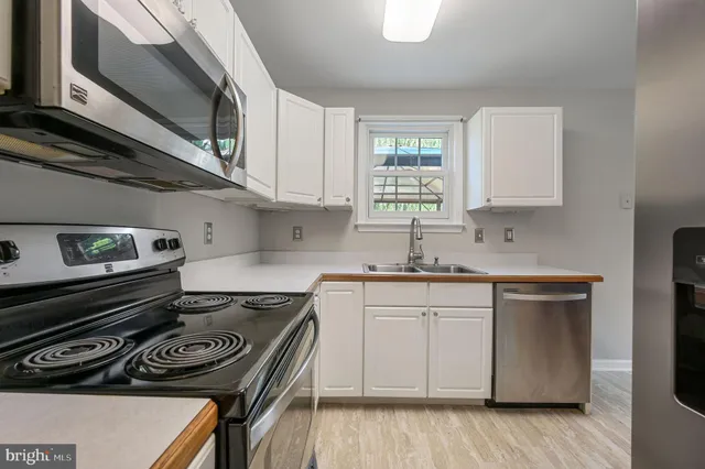 a kitchen with a stove a sink and wooden floor
