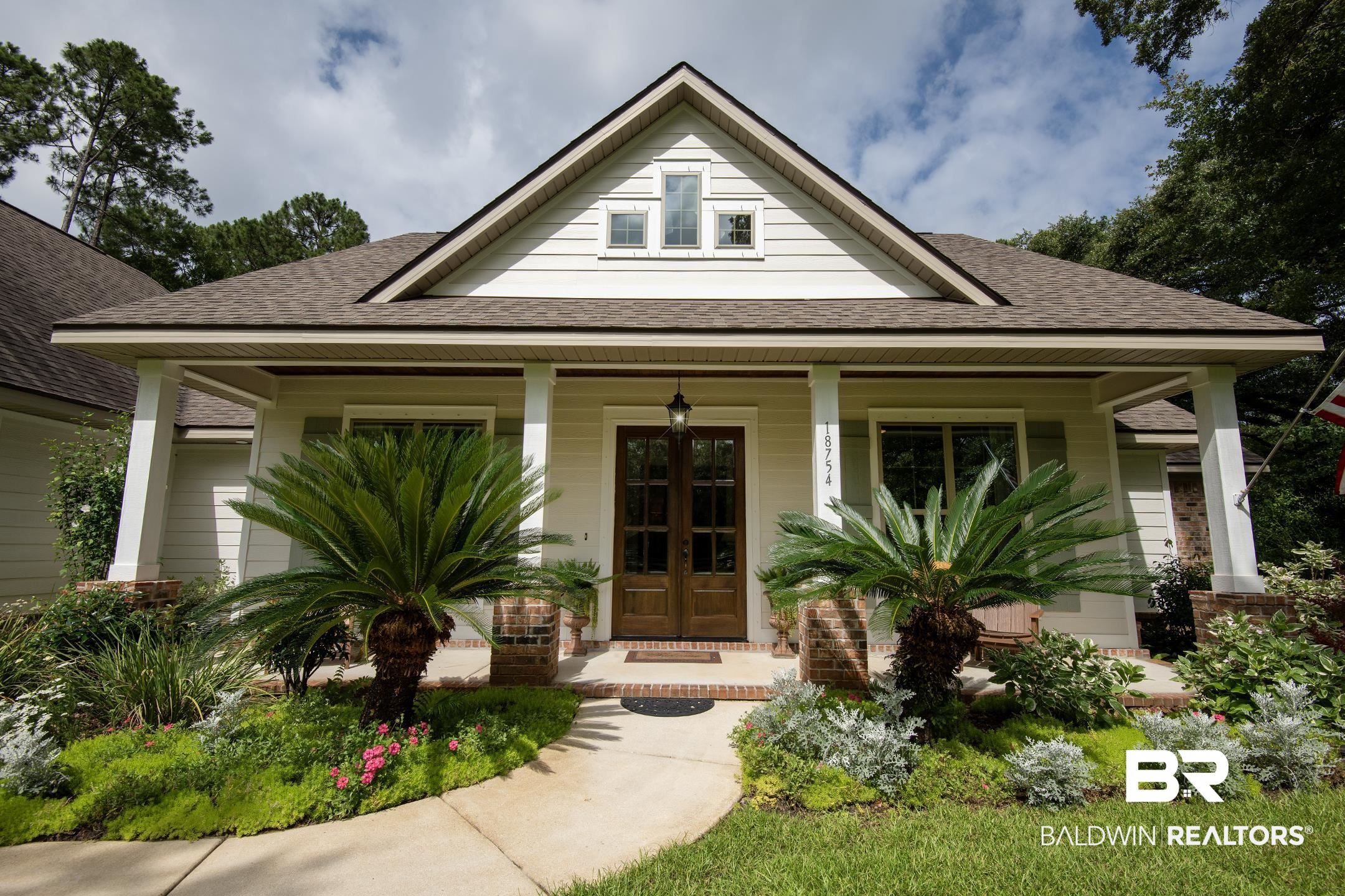 18754 Treasure Oaks Road Gulf Shores, AL 36542 - Photo 6 of 53 Craftsman-style exterior featuring a covered porch with white columns, a dark wood double-door entry, light-colored siding, and a gabled roof