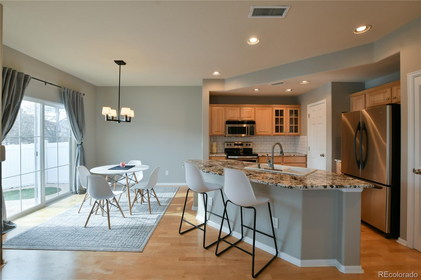 156 Whitehaven Circle Highlands Ranch, CO 80129 - Photo 10 of 30 a kitchen with stainless steel appliances kitchen island granite countertop a dining table chairs refrigerator and sink