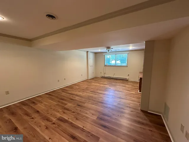 a view of empty room with wooden floor and fan