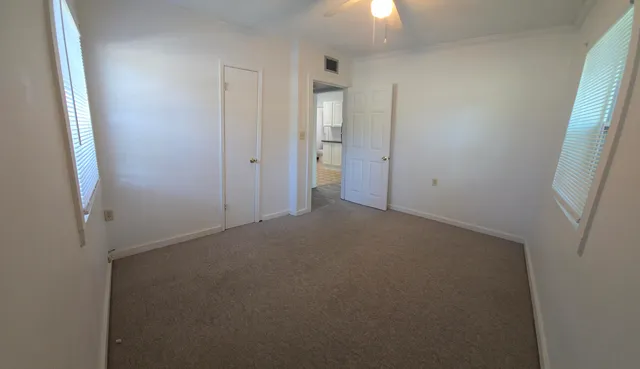an empty room with windows and entrance to other room