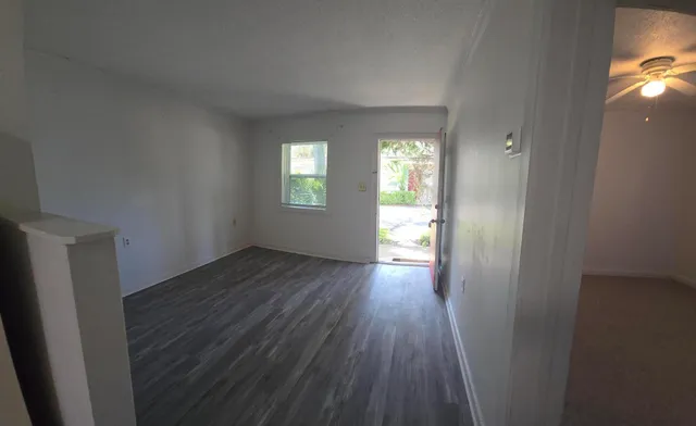 an empty room with wooden floor and windows