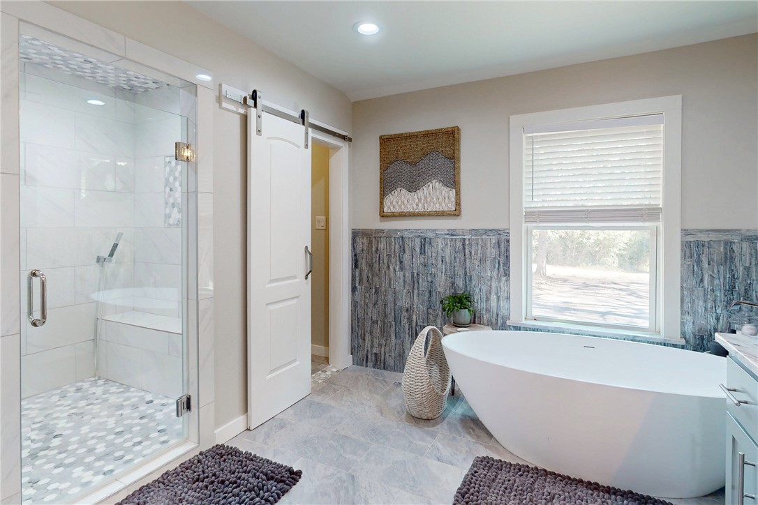 11092 Riley Green Road Franklin, TX 77856 - Photo 17 of 32 Bathroom featuring plus walk in shower, tile walls, and vanity
