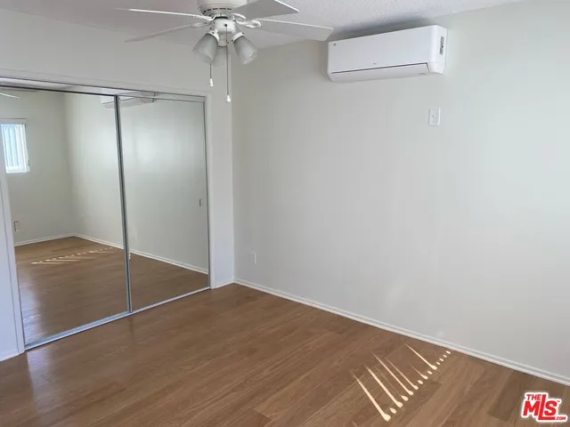 an empty room with wooden floor and fan view