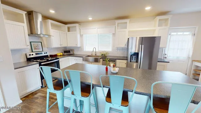 a kitchen with stainless steel appliances kitchen island granite countertop a table chairs refrigerator and microwave