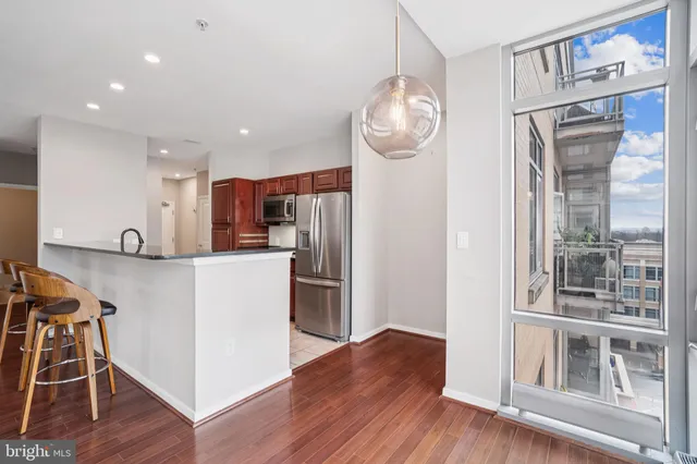 a kitchen with stainless steel appliances a refrigerator and a wooden floor