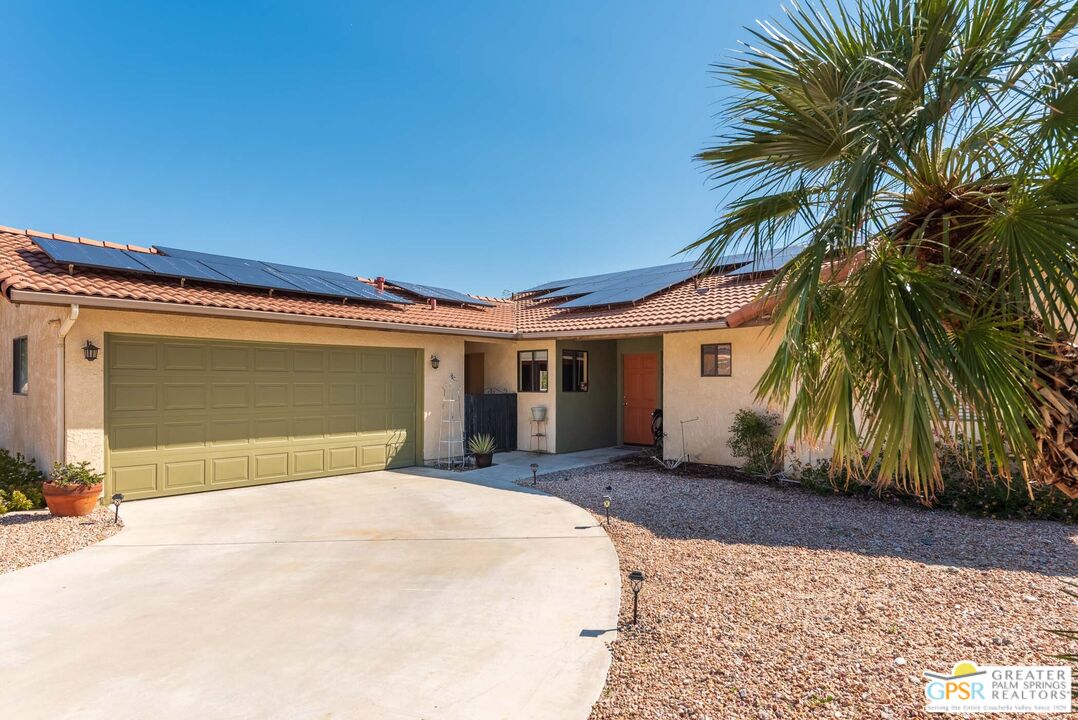 9760 Capiland Road Desert Hot Springs, CA 92240 - Photo 2 of 16 a front view of a house with a yard and garage