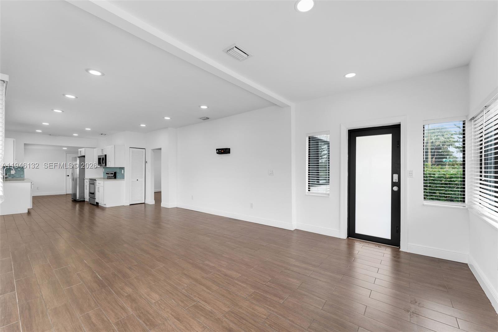 5790 Southwest 5th Street, Unit FRONT Miami, FL 33144 - Photo 5 of 12 a view of an empty room with wooden floor and a window