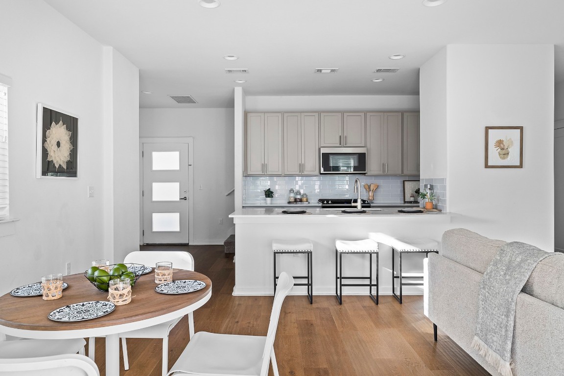 6800 Menchaca Road, Unit 22 Austin, TX 78745 - Photo 4 of 28 Kitchen with a breakfast bar, stainless steel microwave, a peninsula, tasteful backsplash, and gray cabinetry