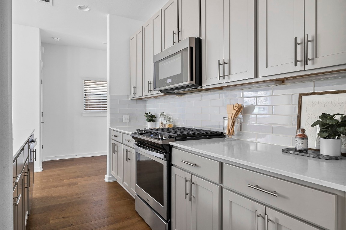 6800 Menchaca Road, Unit 22 Austin, TX 78745 - Photo 6 of 28 Kitchen featuring stainless steel appliances, dark wood-style flooring, gray cabinets, light stone counters, and recessed lighting