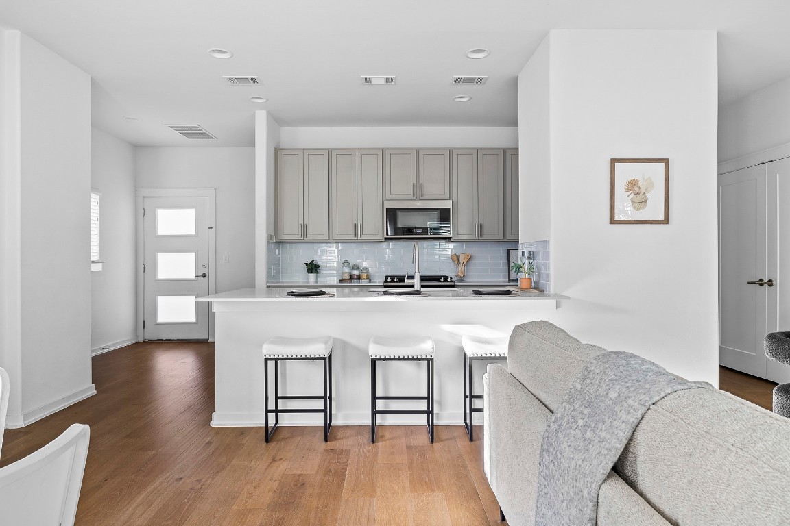 6800 Menchaca Road, Unit 22 Austin, TX 78745 - Photo 28 of 28 Kitchen featuring gray cabinets, a kitchen breakfast bar, decorative backsplash, open floor plan, and a peninsula