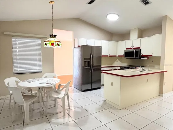 a kitchen with stainless steel appliances kitchen island granite countertop a refrigerator a stove a microwave oven a sink with island and chairs