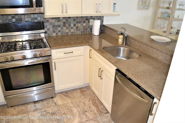 a kitchen with granite countertop a sink a stove and refrigerator