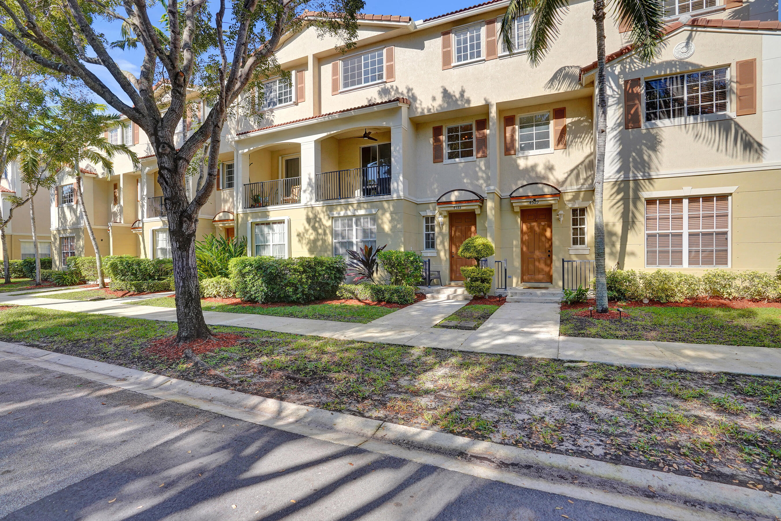 4533 Danson Way Delray Beach, FL 33445 - Photo 58 of 92 a view of a brick house with many windows next to a yard