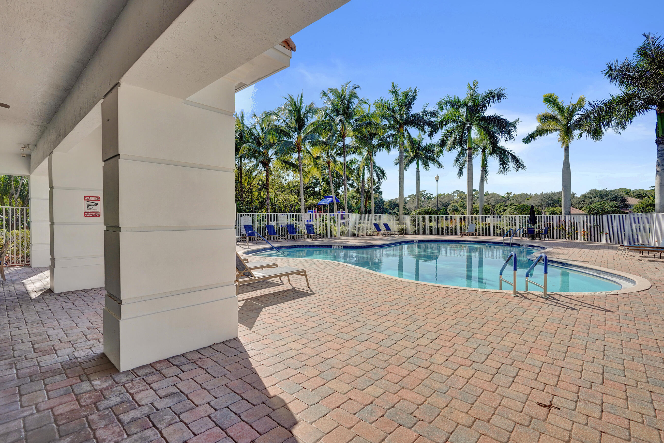 4533 Danson Way Delray Beach, FL 33445 - Photo 63 of 92 a view of a swimming pool with a chair and palm trees