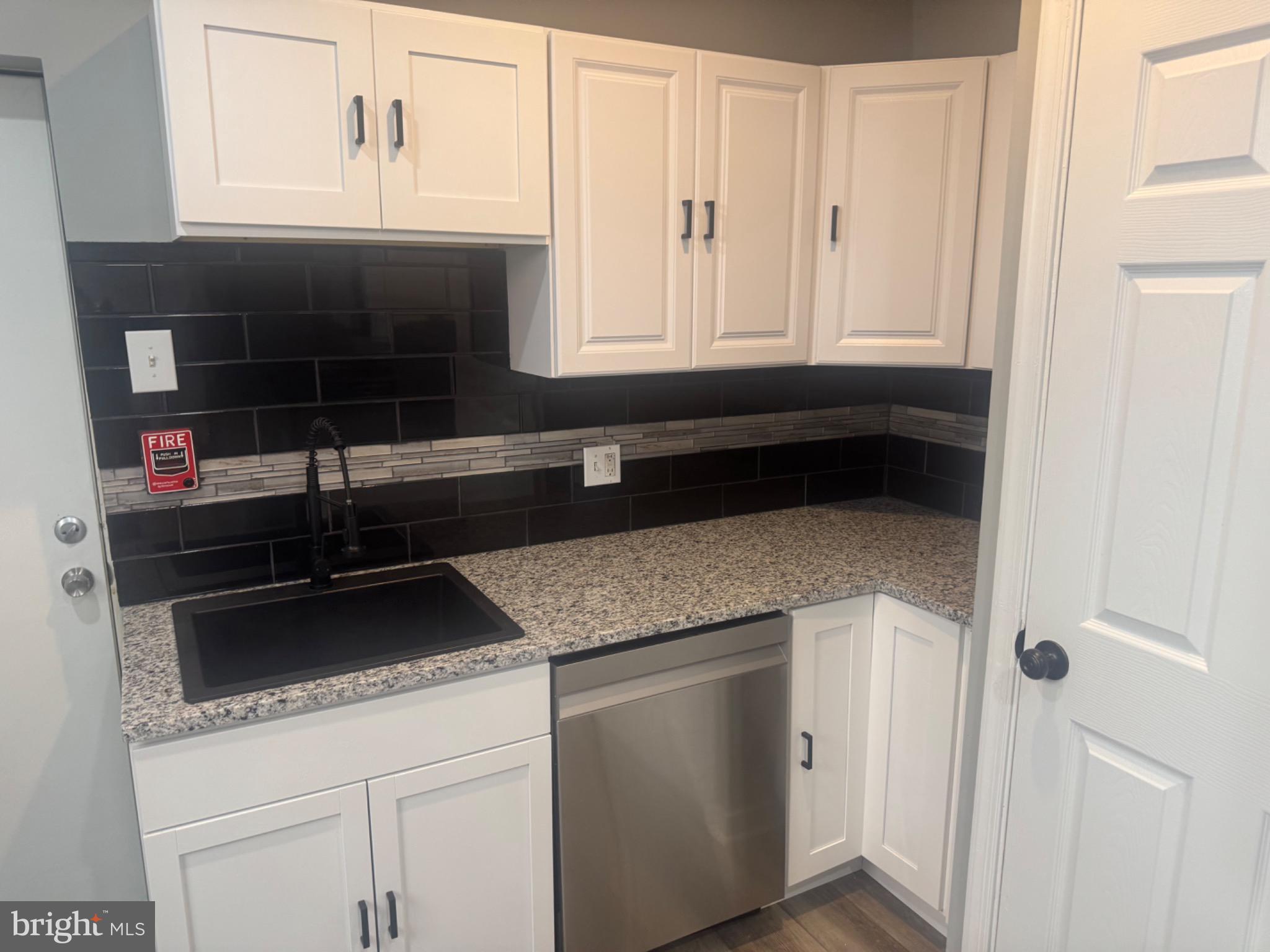 1717 North 26th Street, Unit 1 Philadelphia, PA 19121 - Photo 2 of 11 a kitchen with granite countertop white cabinets and black appliances