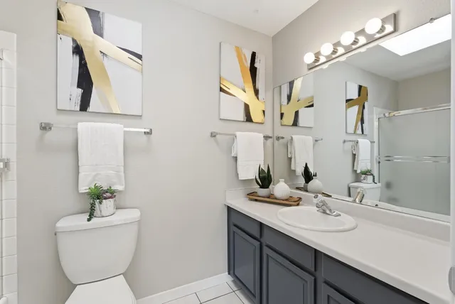 a bathroom with a granite countertop sink a toilet and mirror