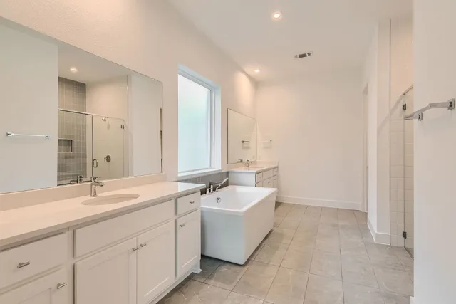 a bathroom with a double vanity sink mirror and bathtub