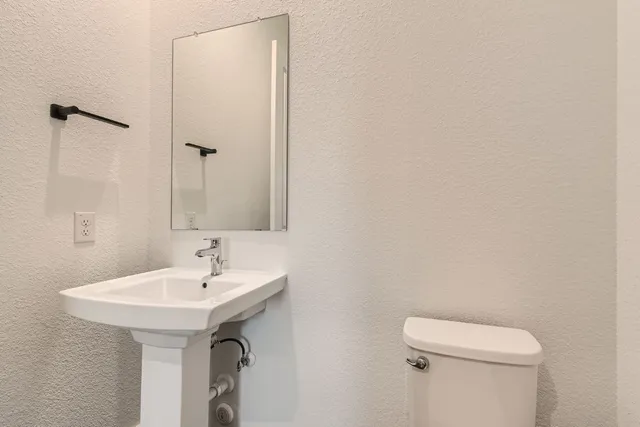 a bathroom with a sink a toilet and a mirror