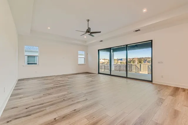 a view of an empty room with window and wooden floor