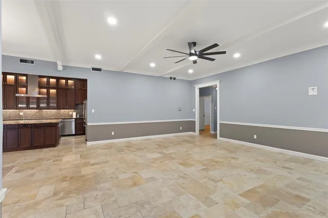a view of an empty room with kitchen appliances and a ceiling fan