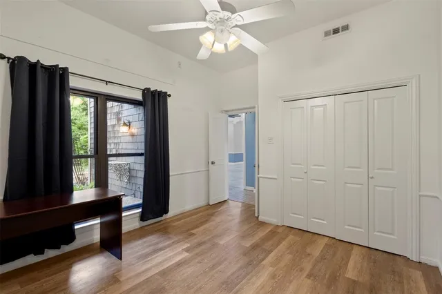 an empty room with wooden floor and a ceiling fan