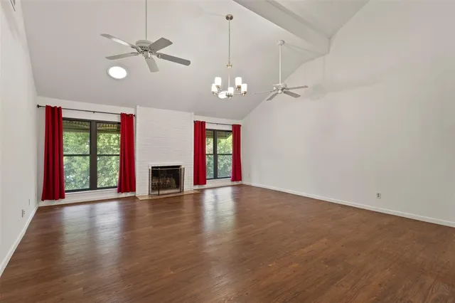 a view of empty room with wooden floor fan and windows