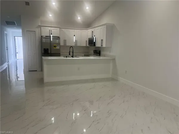 a view of a refrigerator in kitchen and an empty room